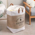 Cream white foldable laundry basket with leather handles in living room