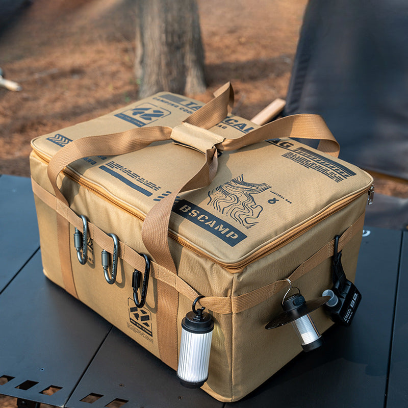 Camping bag with carabiners, straps, and mini lantern attachment on an outdoor table.