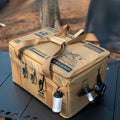 Camping bag with carabiners, straps, and mini lantern attachment on an outdoor table.