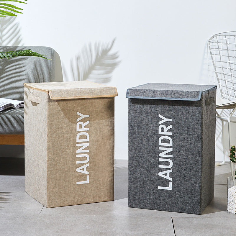 Gray and khaki lidded laundry baskets with LAUNDRY text, shown side by side in a modern bedroom setting
